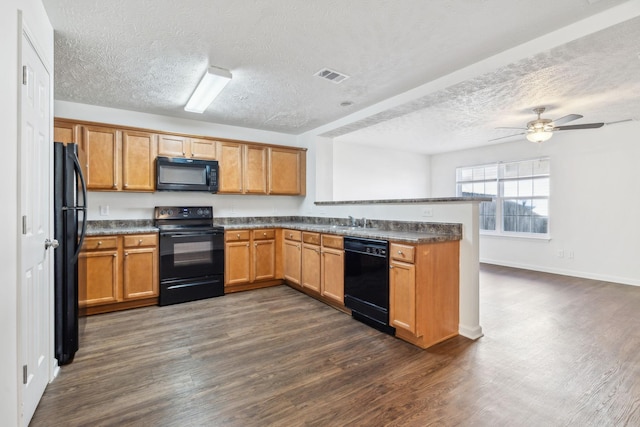 kitchen with a peninsula, black appliances, visible vents, and dark wood-type flooring