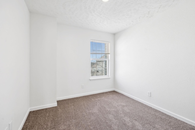 empty room with carpet, baseboards, and a textured ceiling