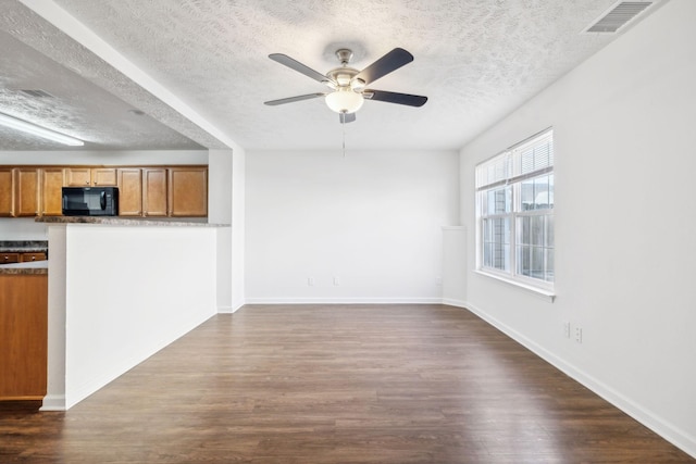 unfurnished living room featuring a textured ceiling, visible vents, baseboards, a ceiling fan, and dark wood-style floors