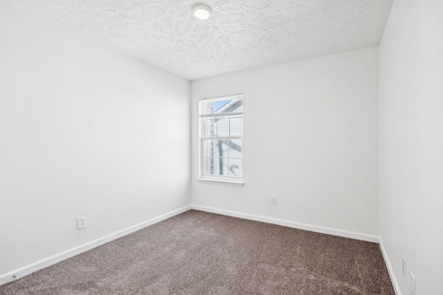 spare room with baseboards, dark carpet, and a textured ceiling