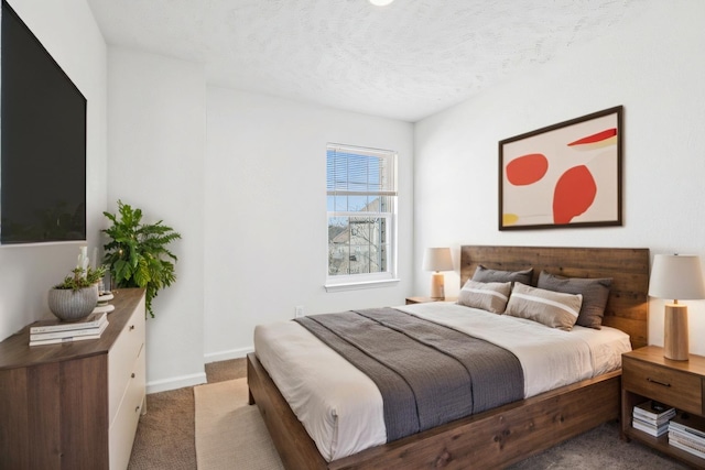 carpeted bedroom featuring a textured ceiling and baseboards