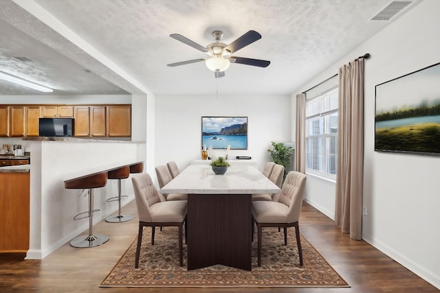 dining room featuring visible vents, dark wood finished floors, a textured ceiling, and baseboards