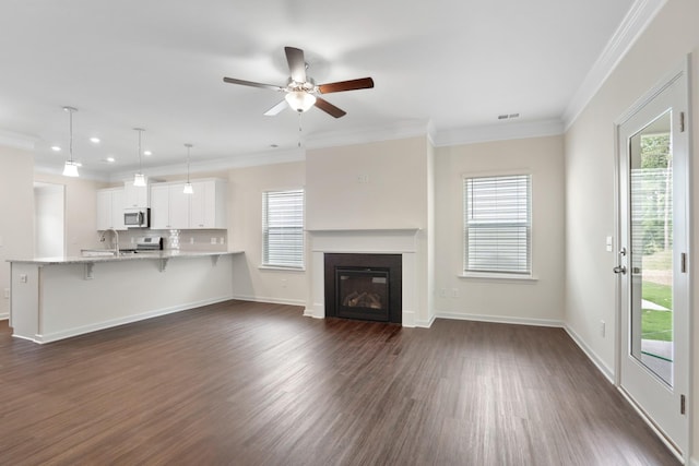 unfurnished living room featuring ornamental molding, dark wood-type flooring, sink, and ceiling fan