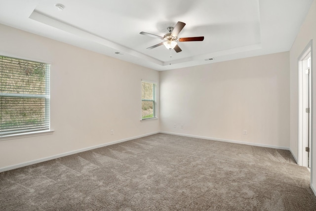 spare room featuring ceiling fan, a tray ceiling, and carpet