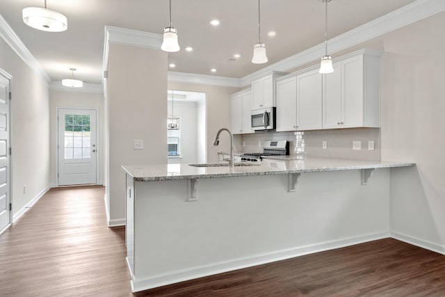 kitchen featuring pendant lighting, sink, stainless steel appliances, white cabinets, and kitchen peninsula