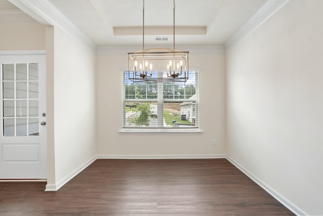 unfurnished dining area featuring a raised ceiling, ornamental molding, dark wood-type flooring, and an inviting chandelier