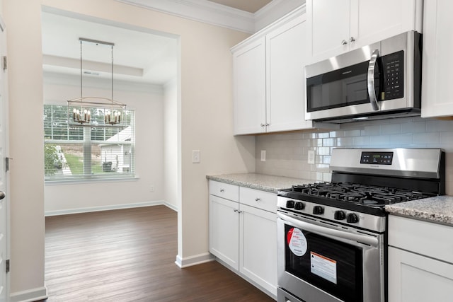 kitchen with appliances with stainless steel finishes, white cabinets, decorative backsplash, ornamental molding, and light stone counters