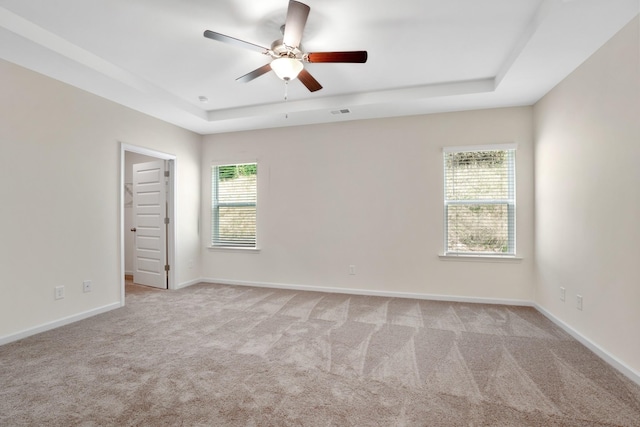 carpeted spare room with ceiling fan and a tray ceiling