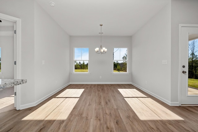 unfurnished dining area with an inviting chandelier and light hardwood / wood-style floors