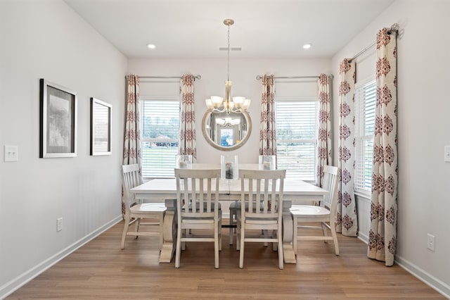 dining area with light wood-type flooring and an inviting chandelier