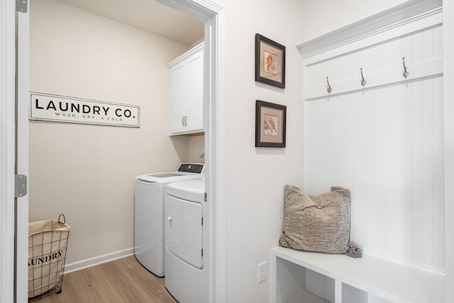 laundry room featuring cabinets, light hardwood / wood-style floors, and washing machine and clothes dryer