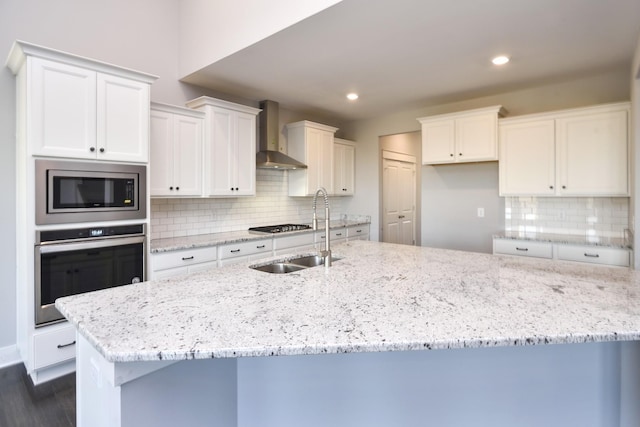 kitchen featuring sink, backsplash, stainless steel appliances, white cabinets, and wall chimney exhaust hood