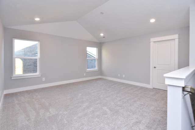 spare room featuring light colored carpet and vaulted ceiling