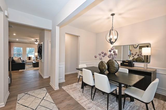 dining room with hardwood / wood-style flooring and ceiling fan with notable chandelier