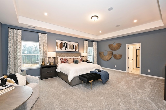 carpeted bedroom featuring a raised ceiling and multiple windows