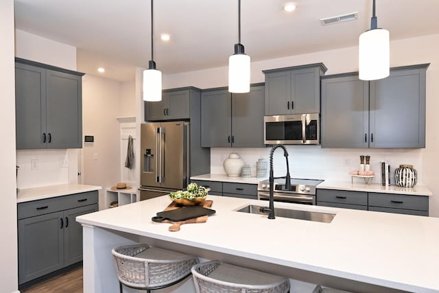 kitchen featuring stainless steel appliances, tasteful backsplash, gray cabinetry, and pendant lighting