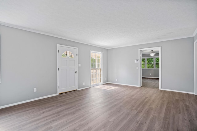 spare room featuring wood-type flooring, a healthy amount of sunlight, crown molding, and a textured ceiling