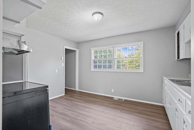 unfurnished dining area featuring light hardwood / wood-style floors and a textured ceiling