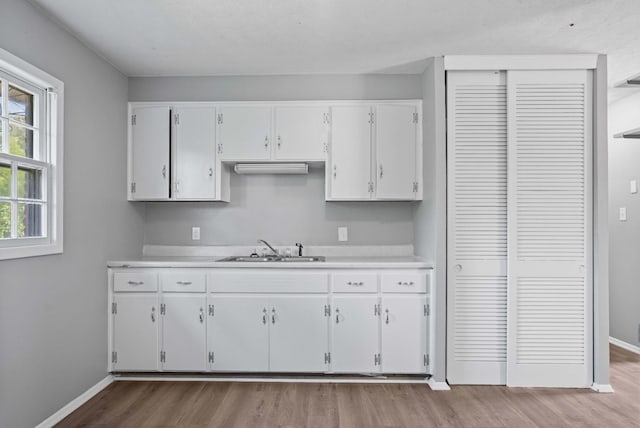 kitchen with white cabinetry, light hardwood / wood-style floors, and sink