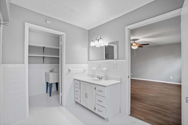 bathroom with hardwood / wood-style floors, vanity, tile walls, and ceiling fan