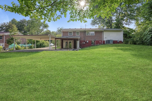 rear view of property featuring a carport, a yard, and central AC unit