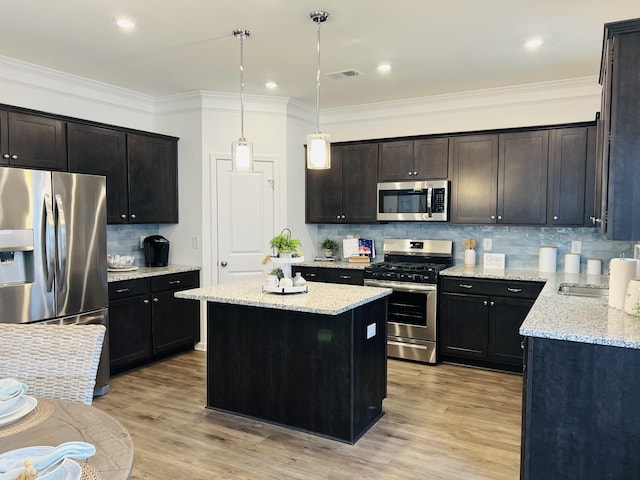 kitchen featuring hanging light fixtures, stainless steel appliances, a center island, light stone countertops, and light wood-type flooring