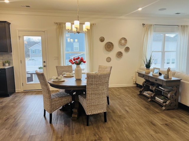 dining room with ornamental molding, dark hardwood / wood-style floors, and an inviting chandelier