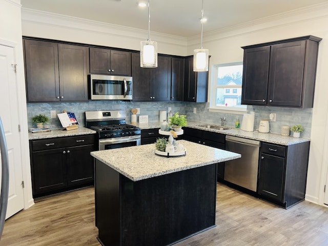 kitchen with hanging light fixtures, a center island, light stone counters, stainless steel appliances, and light wood-type flooring