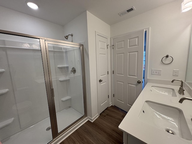 bathroom featuring wood-type flooring, a shower with door, and vanity