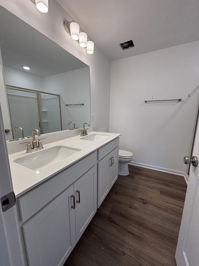 bathroom featuring vanity, hardwood / wood-style flooring, a shower with shower door, and toilet