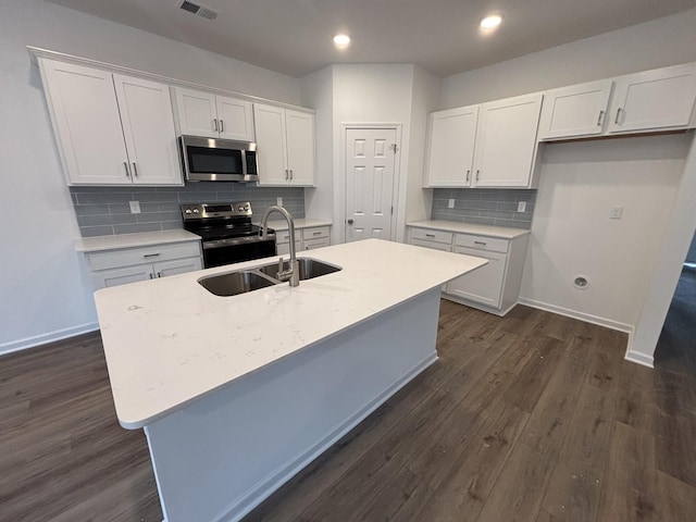 kitchen featuring dark wood-type flooring, sink, a center island with sink, stainless steel appliances, and white cabinets