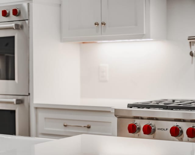 kitchen featuring double wall oven, stainless steel gas cooktop, and white cabinets