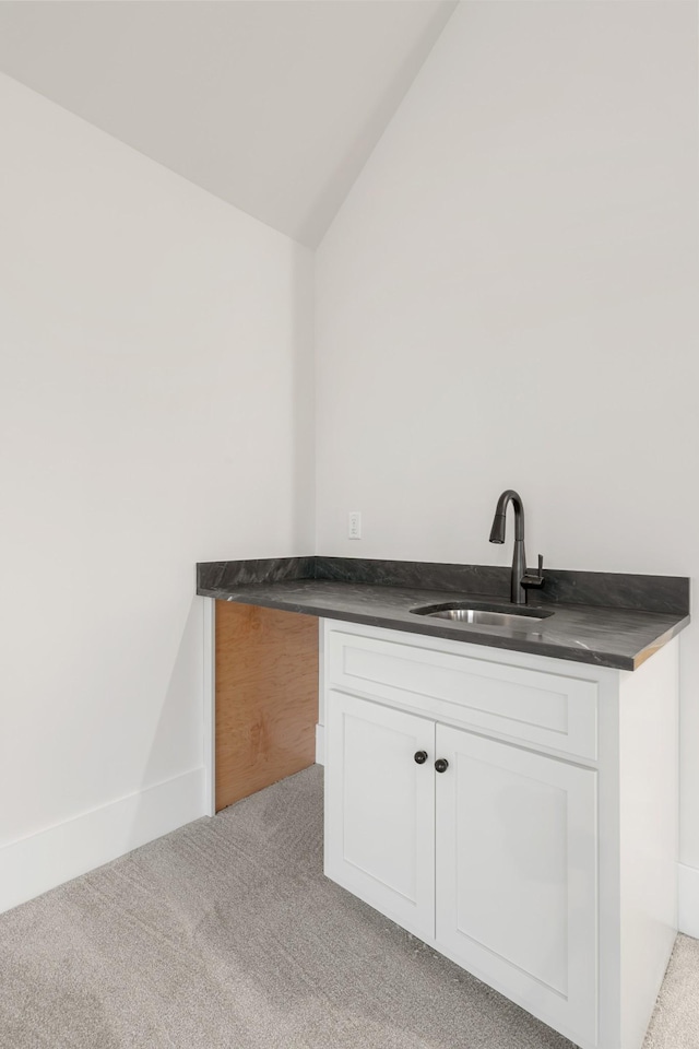 bar with sink, vaulted ceiling, light colored carpet, and white cabinets