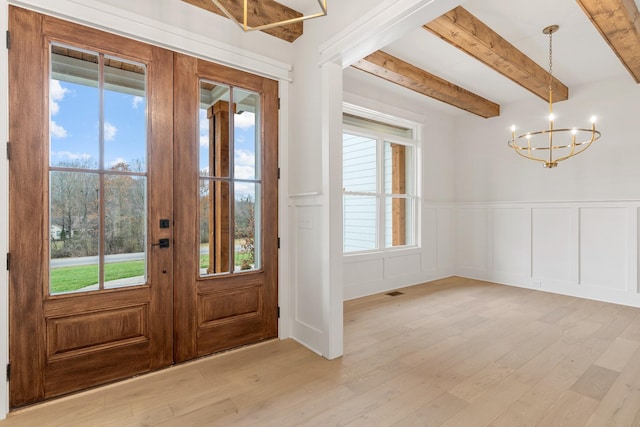 foyer with beamed ceiling, plenty of natural light, and light hardwood / wood-style floors