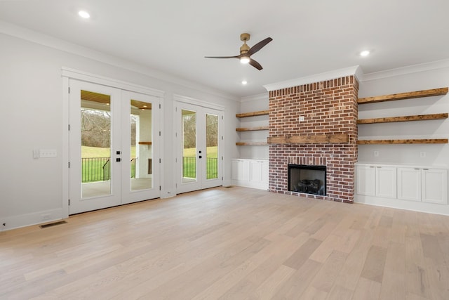 unfurnished living room featuring crown molding, ceiling fan, light hardwood / wood-style floors, a brick fireplace, and french doors