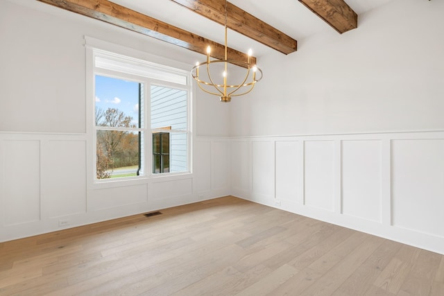 spare room with beam ceiling, light hardwood / wood-style flooring, and a notable chandelier