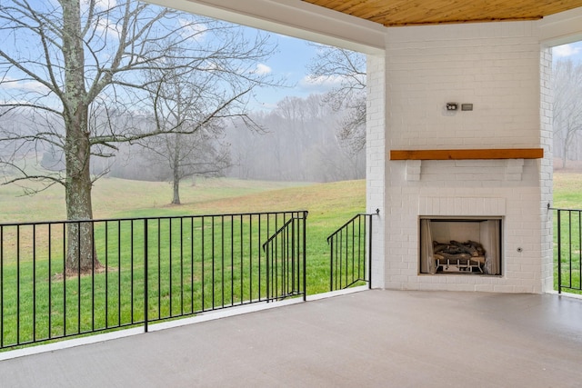 view of patio / terrace with an outdoor brick fireplace and a rural view