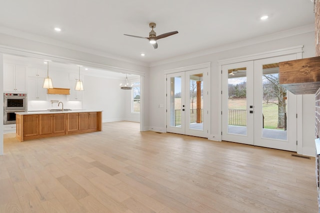 unfurnished living room featuring light hardwood / wood-style floors, ornamental molding, french doors, and ceiling fan