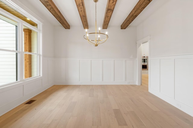 empty room featuring beamed ceiling, a chandelier, and light wood-type flooring