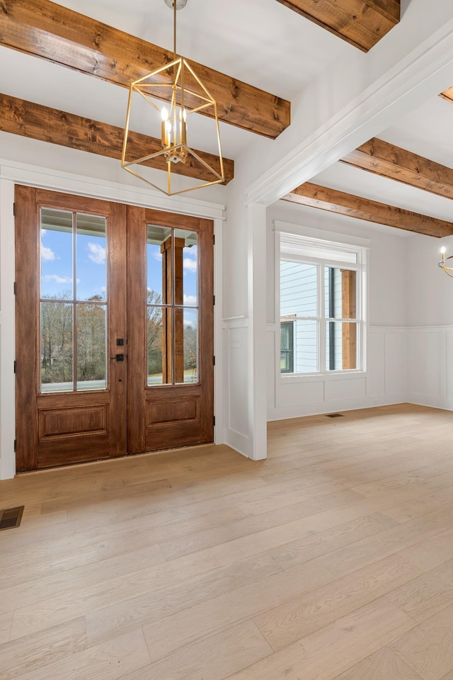 entryway with beamed ceiling, a healthy amount of sunlight, and an inviting chandelier