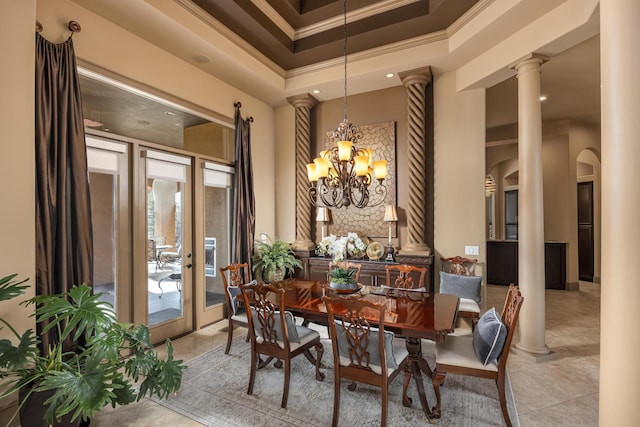 tiled dining area with crown molding, a tray ceiling, an inviting chandelier, and ornate columns