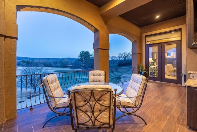 patio terrace at dusk with french doors, a balcony, and a mountain view