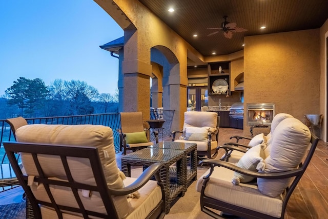 patio terrace at dusk featuring exterior kitchen, grilling area, and ceiling fan