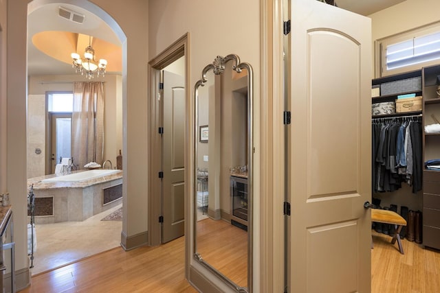 hallway featuring a chandelier and light hardwood / wood-style flooring