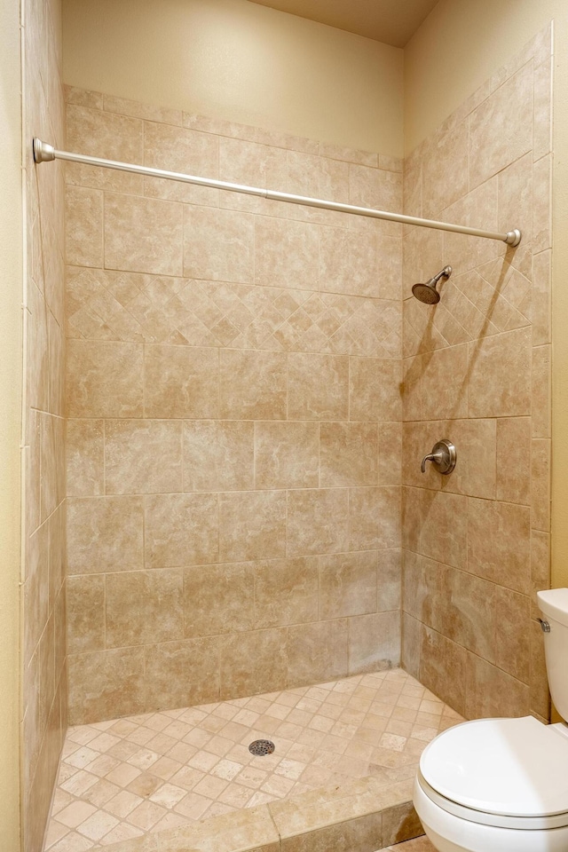 bathroom featuring tiled shower and toilet