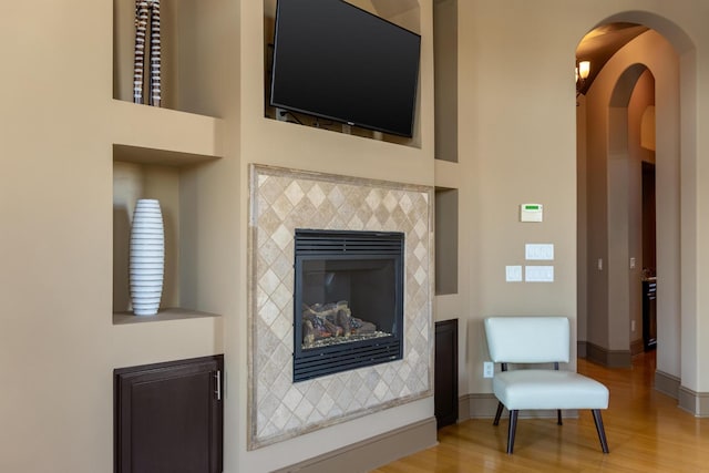 living room with a tiled fireplace and wood-type flooring