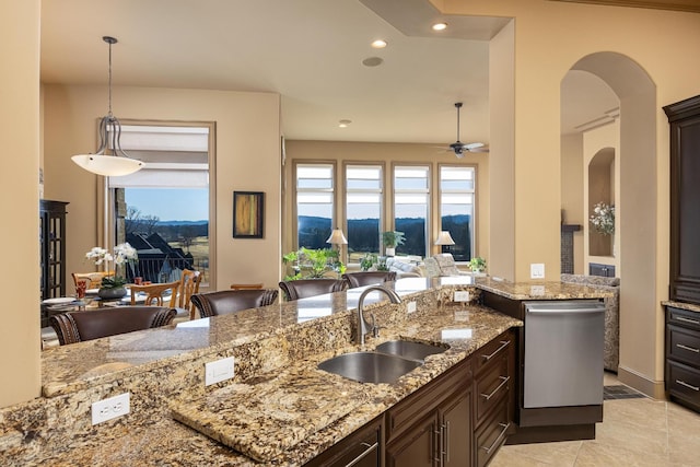 kitchen featuring sink, stainless steel dishwasher, a healthy amount of sunlight, and light stone countertops