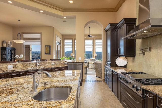 kitchen with sink, decorative light fixtures, wall chimney exhaust hood, and appliances with stainless steel finishes