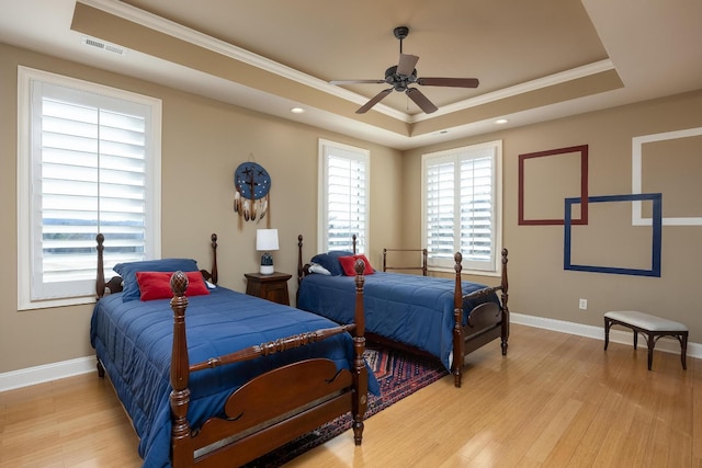 bedroom featuring crown molding, ceiling fan, a raised ceiling, and light hardwood / wood-style flooring