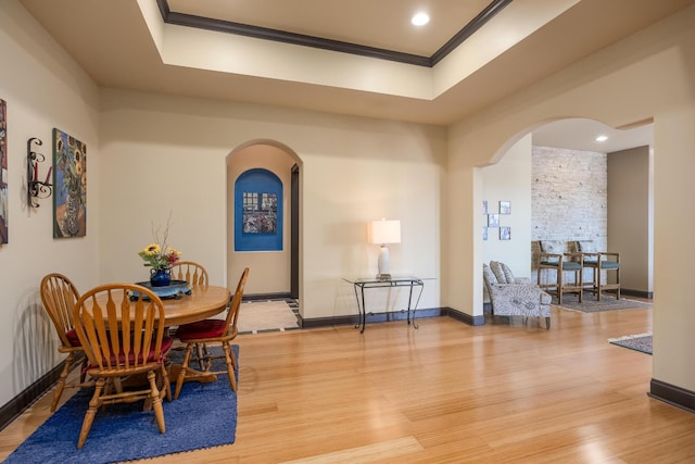 dining room with a tray ceiling, crown molding, and hardwood / wood-style flooring